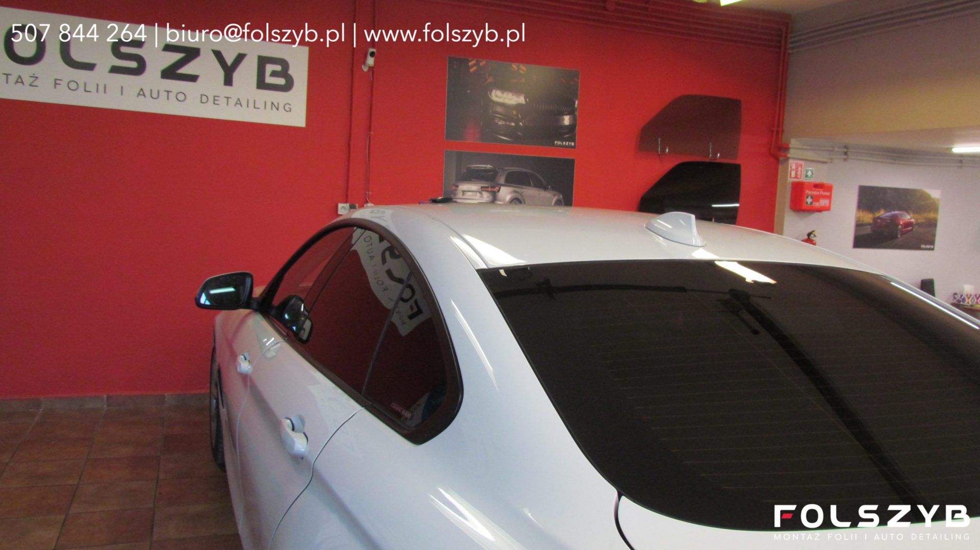 Białe BMW Gran Coupé z folią na szybach za kierowcą w hali FOLSZYB